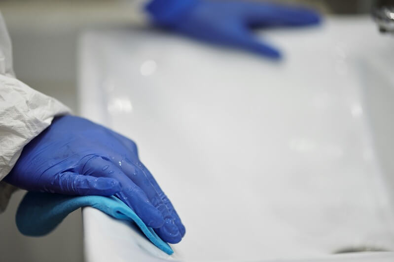 Image of a gloved hand wiping a bathtub clean